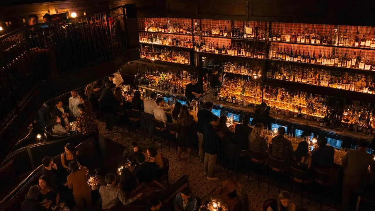 A softly lit bar room with a glowing back bar and a full evening crowd